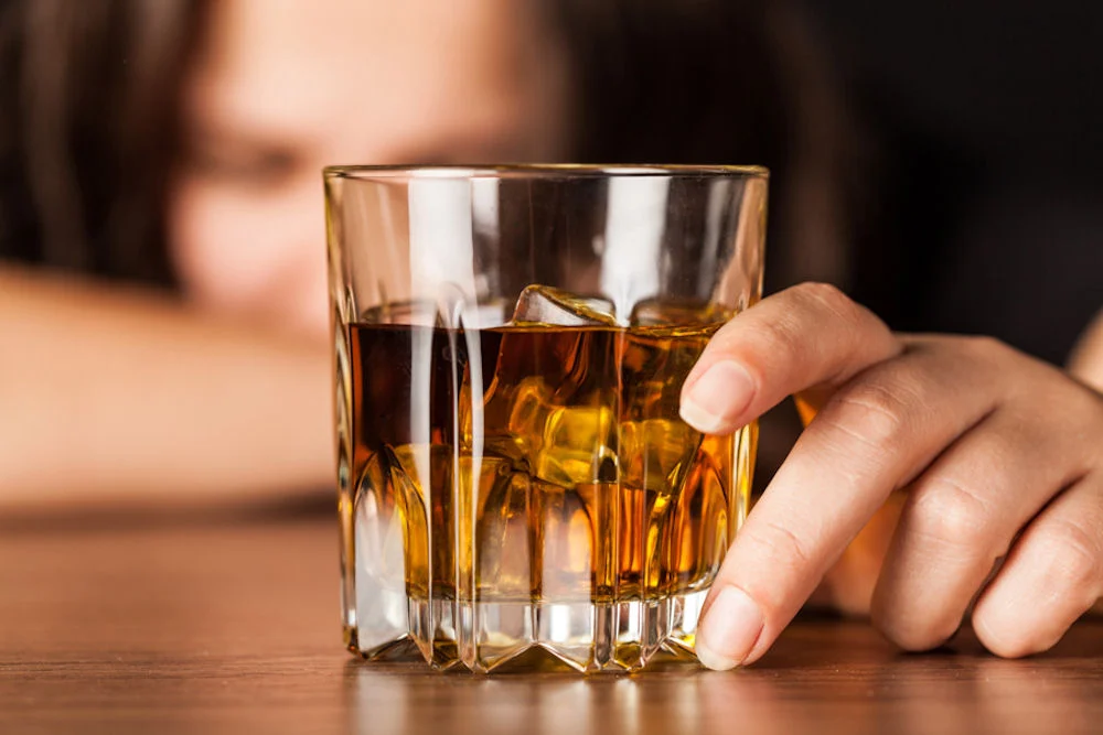 Drunk Woman Sleeping At Bar Counter Holding a Glass of Whisky