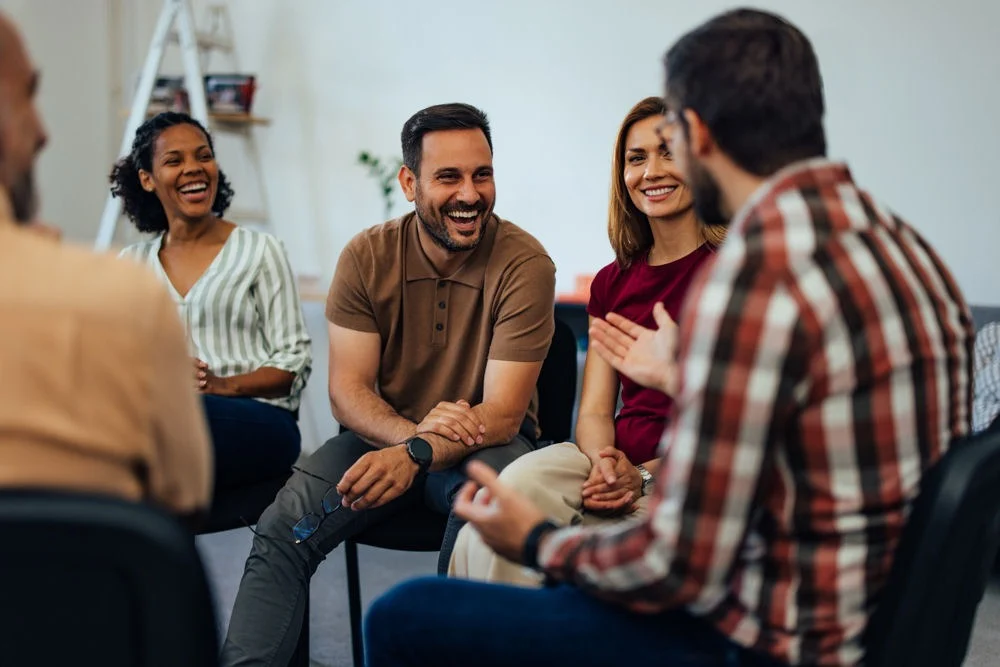 factors-affecting-rehab-success-rates a group of individuals laughing and smiling in therapy