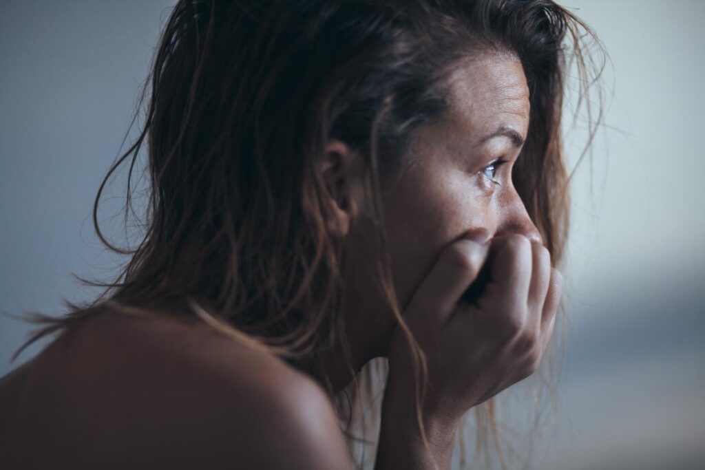 a person holds their face in their hands looking scared possibly wondering why is heroin so addictive
