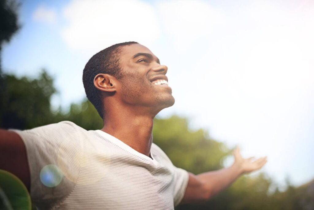 a person smiles happily outside after the impact of dual diagnosis
