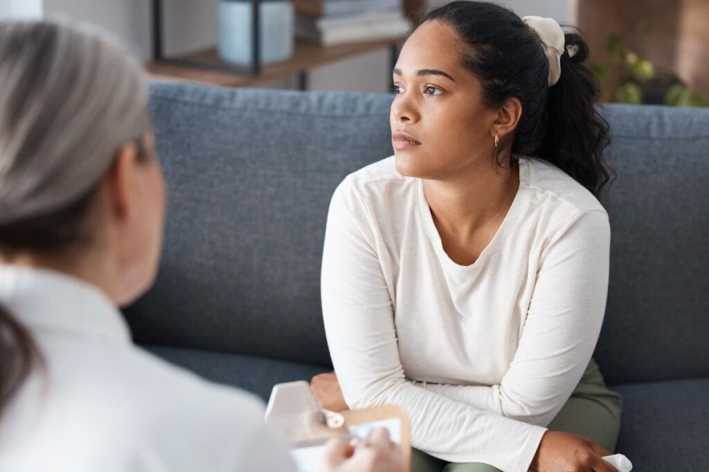 a person looks forlorn while sitting on a couch and learning about the benefits of an anxiety treatment center