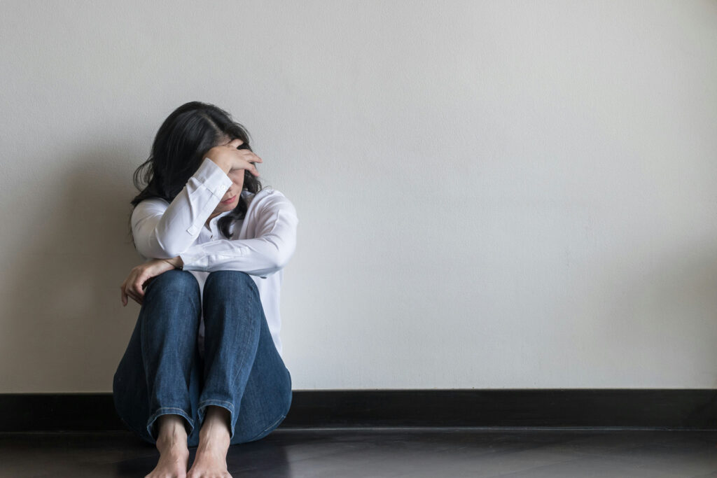 Upset woman sitting on the floor with head in hand, thinking about Adderall for anxiety
