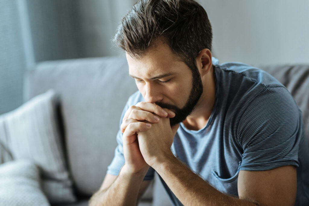a man praying sitting on couch